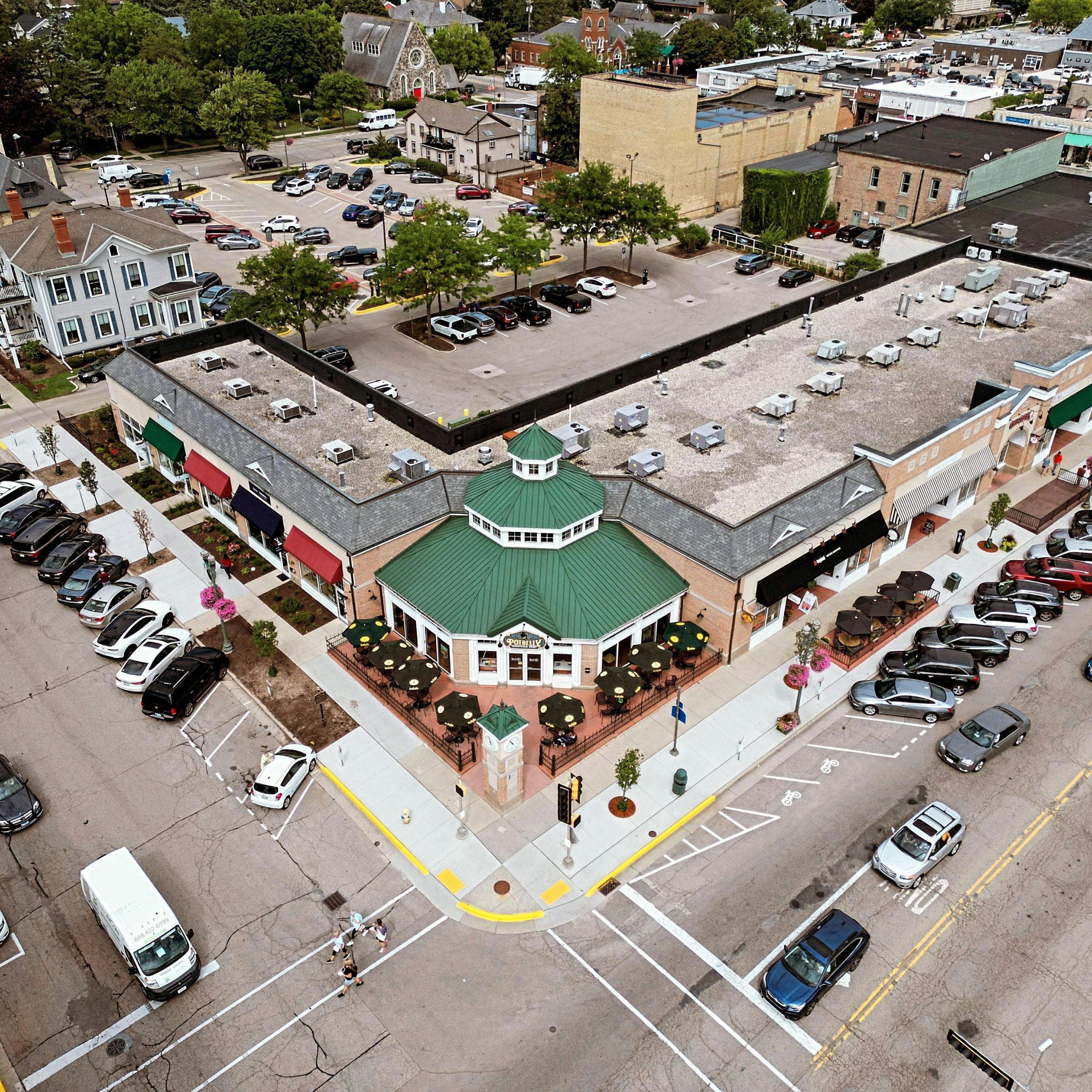 Drone shot of a shopping center and parking lot with distinctive rooftop architecture.